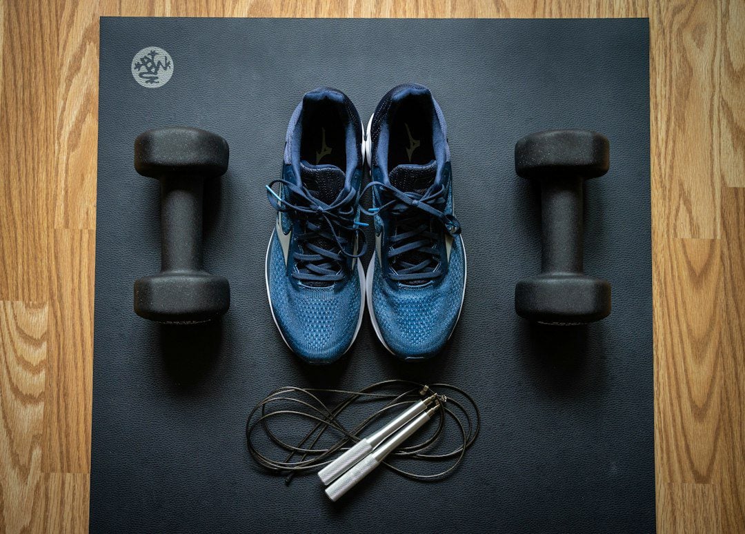 Faceless flat lay of dumbbells and home exercise equipment representing the movement part of a medical weight-loss plan